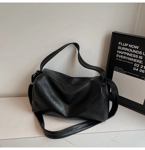 Detailed view of large black tote bag featuring glossy texture and top zipper closure