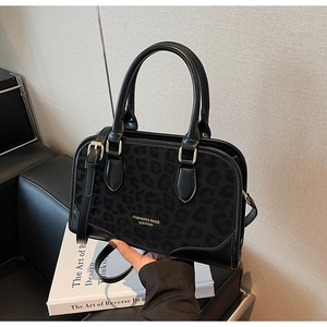 Detail of black leopard pattern Boston bag with gold hardware and leather handles