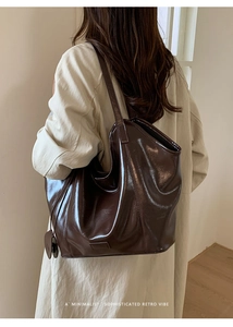 Close-up of a glossy dark brown leather tote bag with retro shoulder strap and charm