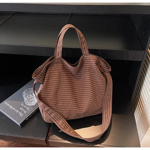 Detail of a brown vintage checkered canvas tote bag with thick texture on a black shelf