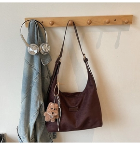 Detail of dark brown suede hobo bag with adjustable strap and cute plush dog pendant