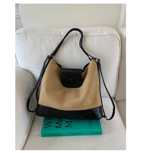Detail view of khaki and black tote bag on white sofa with book accessories