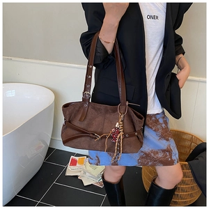 Detail showing brown suede texture of a large tote bag with a polka dot charm