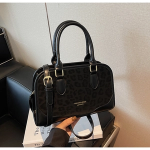 Detail of black leopard print flap bag with gold hardware and embossed fashion logo