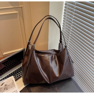Detail of dark brown leather tote bag on leather bench with soft window light shadows