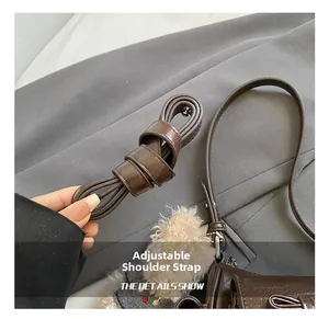 Detail showing the adjustable leather shoulder strap and cute plush charm on a brown bag
