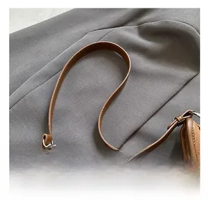 Close-up of brown leather handbag handle with silver hardware and detailed stitching