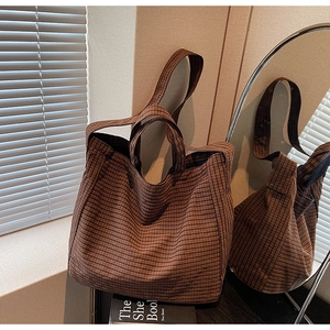 Detail of classic plaid canvas tote bag with double handles in warm sunlight