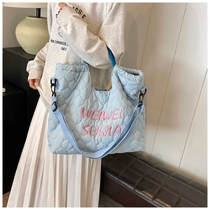 Detail of light blue quilted tote bag with pink embroidery and sturdy nylon shoulder straps