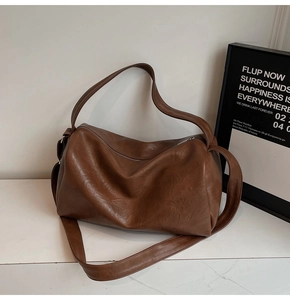 Detailed close-up of brown PU leather tote bag texture and soft pleated design