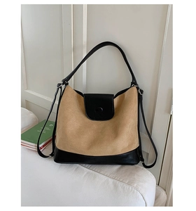 Detailed shot of large contrast tote bag with beige suede texture on white fabric sofa