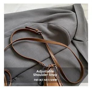 Detail of adjustable brown leather shoulder strap with silver buckle and fine stitching