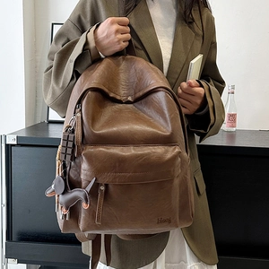 Detail of vintage brown leather backpack with Hoog logo and dachshund charm accessory