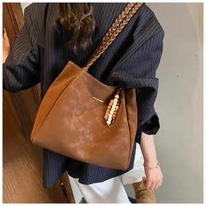 Detail of vintage brown tote bag with braided straps and bohemian beaded tassels