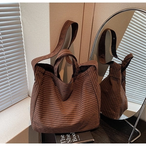 Detail of a large brown checkered canvas tote bag with thick woven straps and textures
