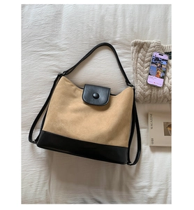 Close-up of contrast tote bag with beige suede fabric and black leather trim details