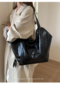 Detail of the large black tote bag featuring glossy faux leather and a wide shoulder strap