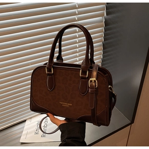 Detail view of dark brown faux leather bag with leopard print texture and gold hardware