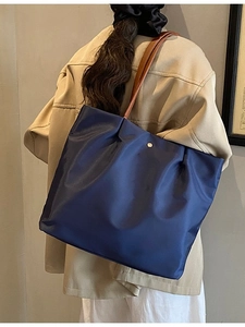 Large navy blue nylon tote bag with brown leather straps shown on model shoulder