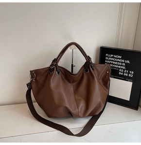 Gros plan du sac cabas en cuir grainé marron avec bandoulière en tissu sur marbre