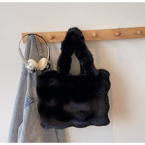 Détail d'un sac cabas en peluche noire avec une texture épaisse en fausse fourrure