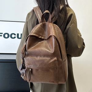 Detail view of the vintage dark brown leather backpack showing texture and zip closure