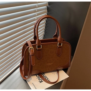 Close-up of brown textured leather handbag featuring leopard pattern and golden hardware