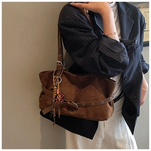 Detail view of vintage brown suede shoulder bag with leather straps and bear accessory