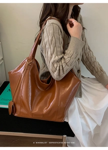 Detail of a large brown glossy tote bag showing textured PU leather and stylish slouchy fit