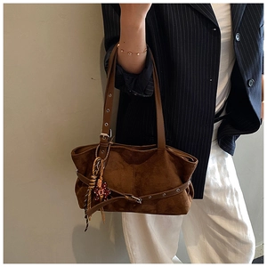 Detail of dark brown suede shoulder bag with adjustable leather strap and charm pendant