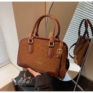 Detail view of brown vintage handbag featuring leopard print suede sides and gold hardware