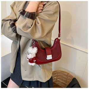 Detail of burgundy hobo bag with suede panels, silver clasp, and cute puppy charm