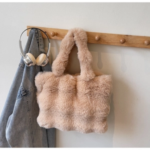 Gros plan d'un sac cabas en fausse fourrure beige suspendu à un crochet en bois