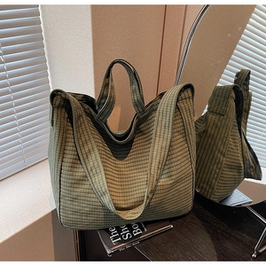 Close-up of green checkered canvas tote bag showing handle detail and fabric texture