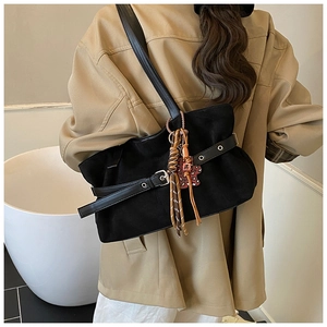 Detail of vintage black suede shoulder bag with silver buckle and colorful tassel charm