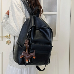 Detail of a black PU leather backpack with cute dog and chocolate charms shown from the back