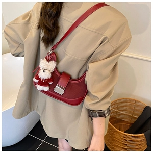 Detail view of burgundy shoulder bag with contrast stitching and plush bear charm accessory
