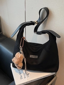 Black suede oversized hobo tote bag with wide strap and brown bear plush charm decor