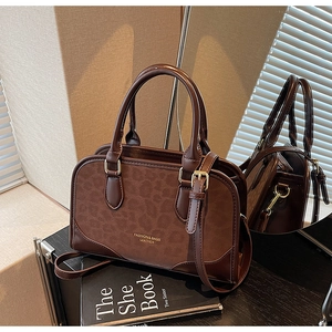 Detailed view of leopard print stitching and golden lettering on dark brown leather bag