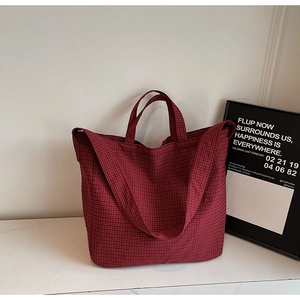 Détail d'un sac cabas à carreaux rouges avec toile épaisse et design à double sangle