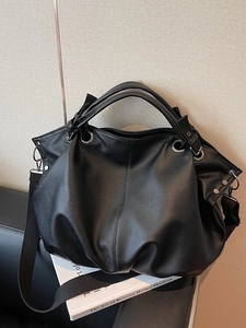 Grand sac cabas noir à texture grainée et design plissé sur canapé en cuir