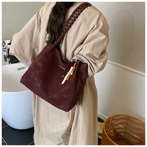 Close-up of burgundy suede tote bag with woven straps and colorful wooden bead charms