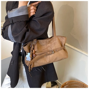 Close-up of vintage brown suede tote bag with metal buckle strap and acrylic charm detail