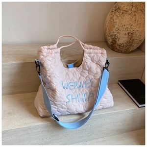 Detail of pink heart-quilted tote bag featuring blue embroidery on marble steps