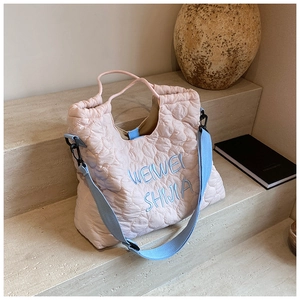 Detail of pink quilted puffer tote with heart patterns and blue embroidered lettering
