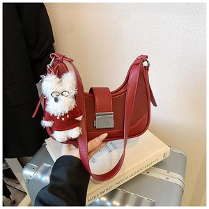 Detail of burgundy crescent shoulder bag with silver clasp and plush puppy charm decor
