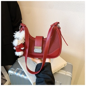 Detail of burgundy hobo bag with silver buckle and cute white plush doll charm