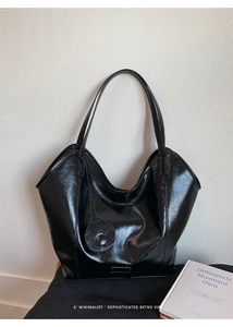 Detail of minimalist black glossy tote bag with vintage texture and circular pendant