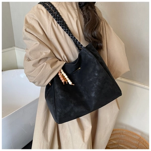 Detail of black suede tote bag with golden lettering and stylish wide woven shoulder strap