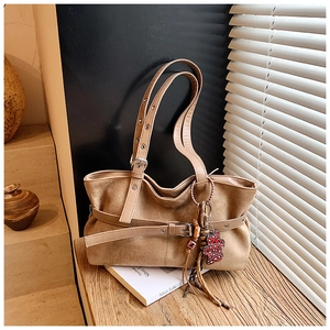 Detail of vintage brown suede tote bag with decorative belt buckle and bear charm